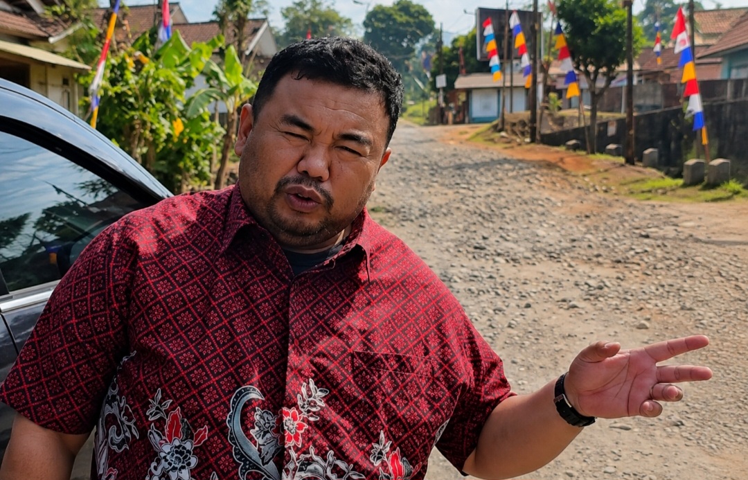 Anggota Fraksi PDI Perjuangan DPRD Kabupaten Garut, Yudha Puja Turnawan, berdiri di pinggir jalan Kecamatan Cihurip yang kondisinya rusak.